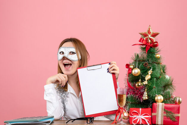 工人戴着派对面具的女工正面图 粉红色的文件说明办公室工作圣诞节