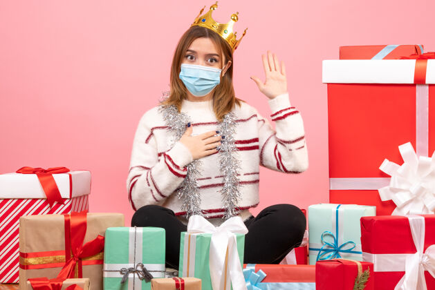 无菌正面图：年轻女性戴着无菌面具围坐在圣诞礼物旁礼物面具人物