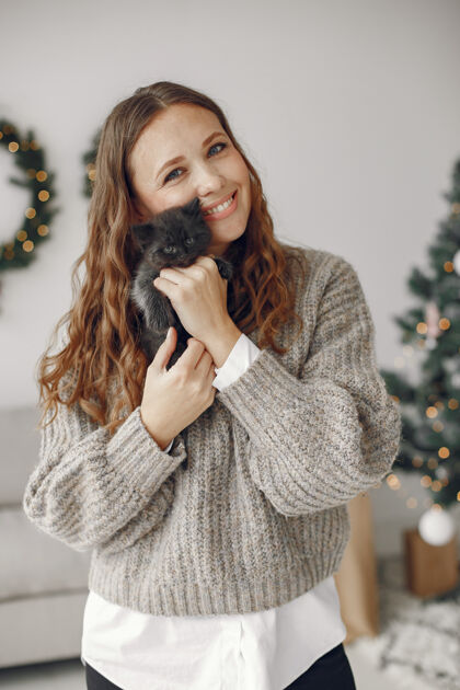 新的房间里的女人穿灰色毛衣的人带着小猫的女人女孩成人快乐