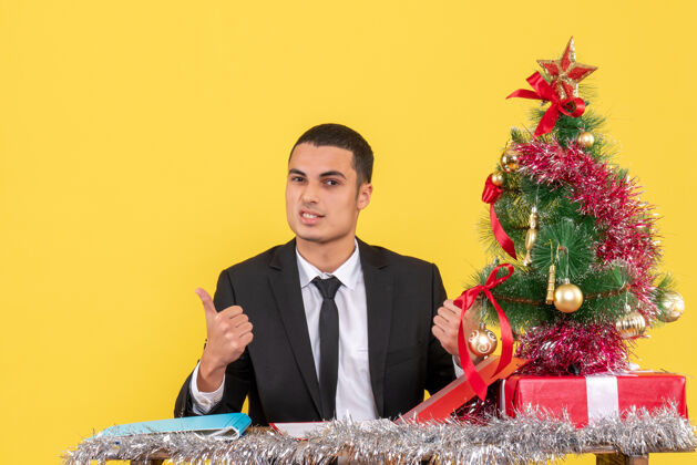 西装正面图西装革履的男人坐在桌子旁 手里拿着文件 上面有圣诞树和礼物坐着新郎文件