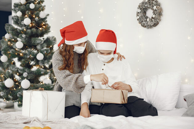 毛衣为圣诞节做准备的人冠状病毒主题妈妈和儿子玩穿白毛衣的男孩孩子闪亮圣诞节