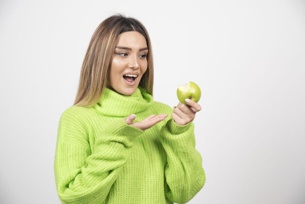 表情穿着绿色t恤的年轻女子手里拿着一个苹果膳食人保持