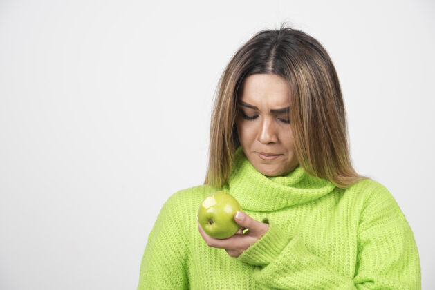 食物穿着绿色t恤的年轻女子手里拿着一个苹果苹果水果T恤