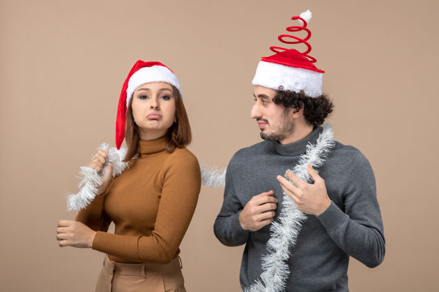 心情新年心情喜庆的概念与兴奋酷满意自信可爱的情侣戴着红色圣诞老人帽灰色兴奋帽子漂亮