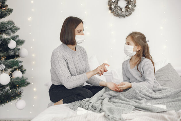 孩子儿童中有冠状病毒母亲带着女儿孩子躺在床上戴着医用口罩的妇女卧室健康床