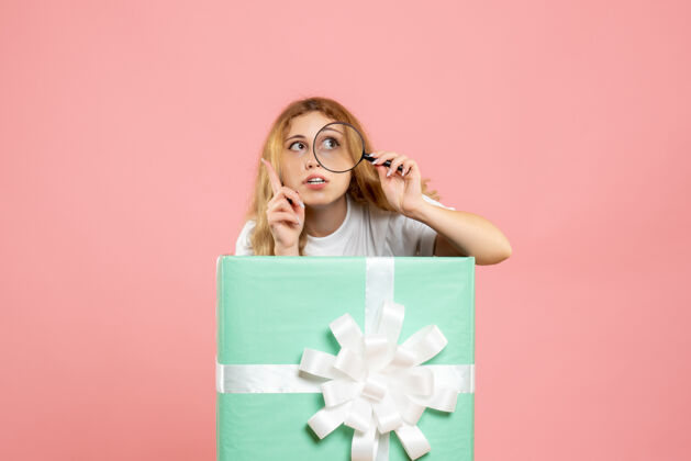 粉色前视图年轻女性在蓝色礼品盒内使用放大镜成人里面情感