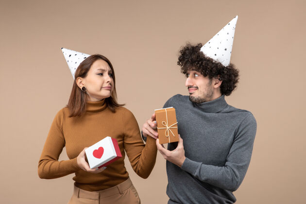 新的新年拍摄与年轻夫妇相视戴新年帽酸溜溜的脸女孩心心帽子情侣