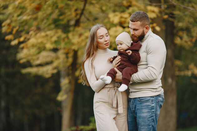 胡须秋天公园里的一家人穿棕色毛衣的男人和父母在一起的可爱小女孩头发成人女性