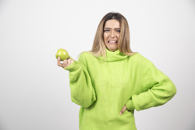 营养穿着绿色t恤的年轻女子手里拿着一个苹果女人维生素人