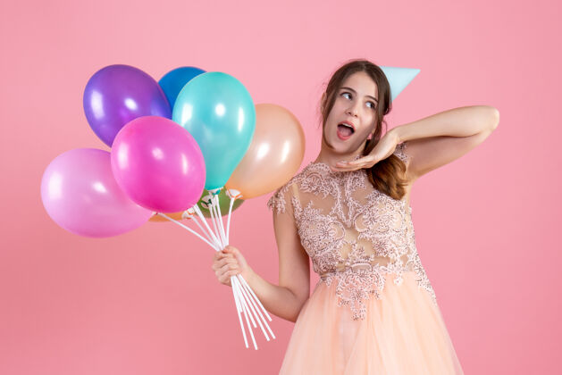 乐趣一个戴着派对帽的惊喜女孩拿着粉红色的气球粉色快乐公主