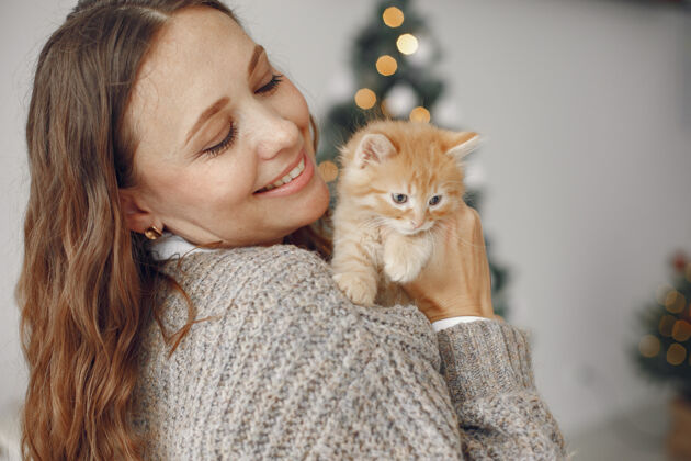 庆祝房间里的女人穿灰色毛衣的人带着小猫的女人惊喜圣诞节欧洲