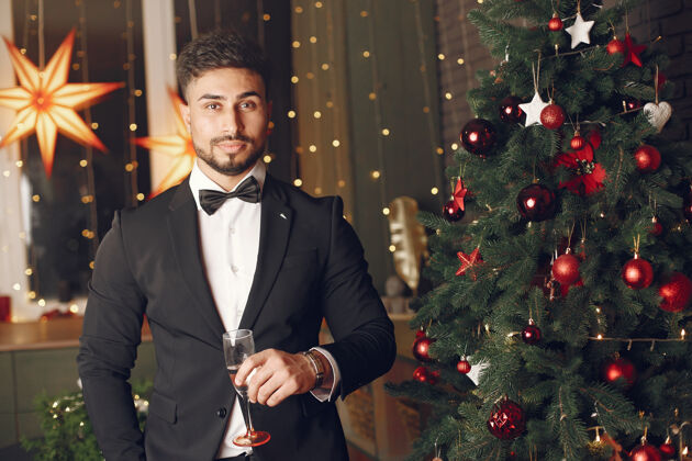 节日圣诞树附近的帅哥穿着黑色西装的绅士印度室内时尚