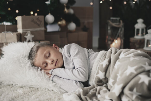 室内睡在地毯上的可爱男孩时间圣诞节做梦