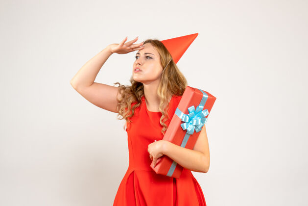 礼物正面图身着红色连衣裙的年轻女性用礼物庆祝圣诞节漂亮成人夏娃