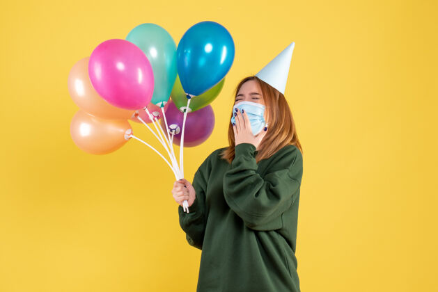 生日正面图戴面具的年轻女性手持五颜六色的气球年轻女性面具气球