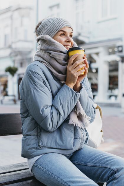 季节性穿着冬衣的年轻女子手里拿着一杯咖啡季节咖啡冬天