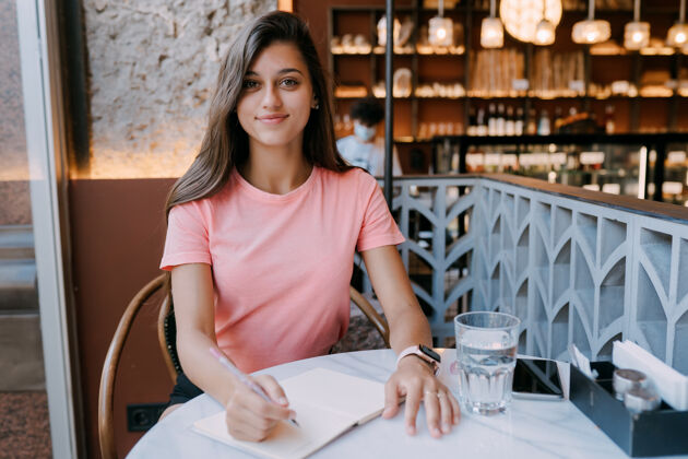 自由职业者在咖啡店的便条上写日记 把概念当作生活的记忆咖啡店的女人微笑的女人做便条业主写作时间