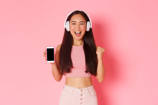年轻一个戴着耳机听音乐的富有表情的年轻女子休闲应用程序夏天