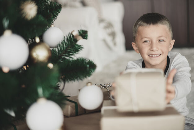 客厅男孩在镜头前展示圣诞礼物摆姿势坐着微笑