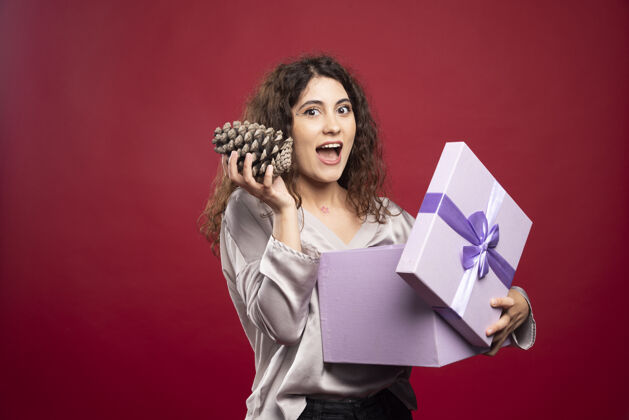 美丽手持紫色礼盒和松果的年轻女子惊喜女性快乐