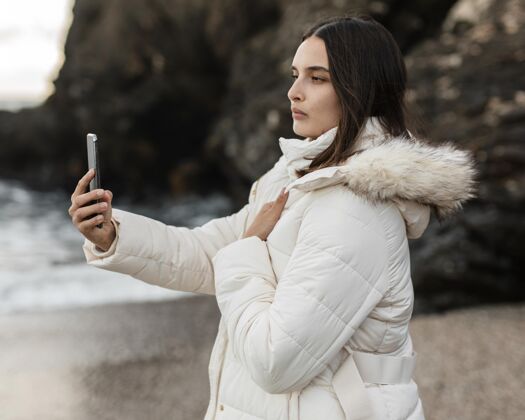 冒险海滩美女用智能手机拍照侧视图旅行航行女人