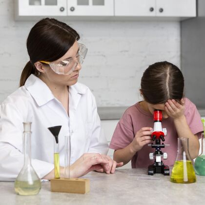 女性小女孩和女老师用显微镜做科学实验测试安全女孩