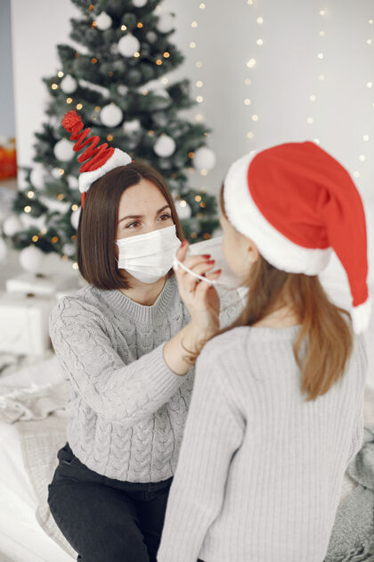 病毒为圣诞节做准备的人冠状病毒主题妈妈和女儿玩穿着灰色毛衣的孩子内部肖像童年