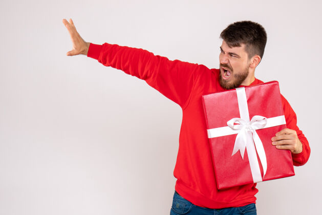 情感身穿红衫的年轻人拿着圣诞礼物站在白墙上的正视图男人节日快乐