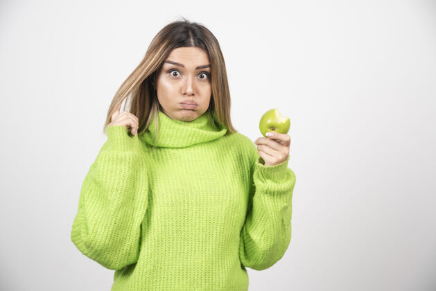 食物穿着绿色t恤的年轻女子手里拿着一个苹果营养年轻肖像