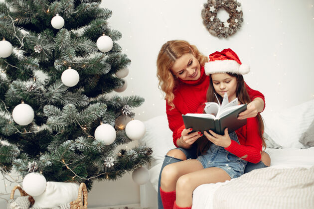 花环人们在为圣诞节做准备母亲在和女儿玩耍一家人在节日的房间里休息孩子穿着红色毛衣家庭传统孩子