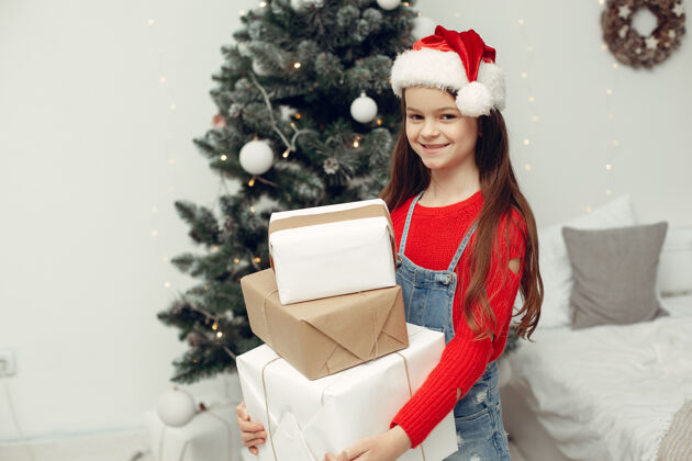 女儿穿白色毛衣的孩子坐在圣诞树旁的女儿小家盒子
