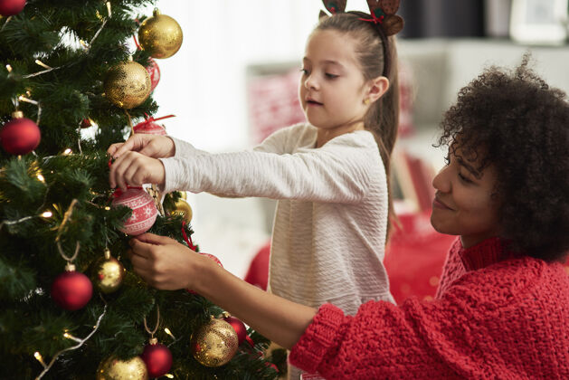 爱可爱的女孩和妈妈在装饰圣诞树房间享受后代