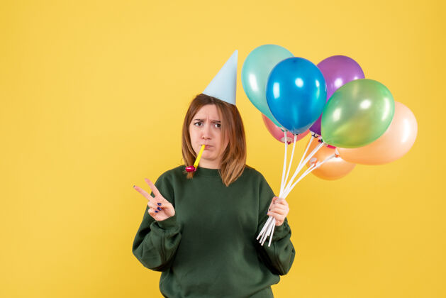 乐趣正面图是一位年轻的女士 手里拿着五颜六色的气球庆祝圣诞节吹