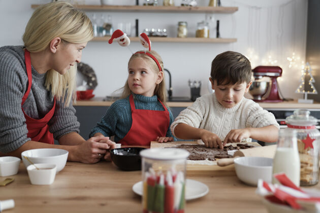 手工制作两个孩子和他们的妈妈切姜饼正面视图糕点自制
