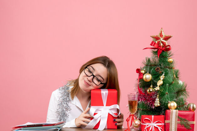 办公室女工手持粉红色礼物的正面图举行肖像圣诞节