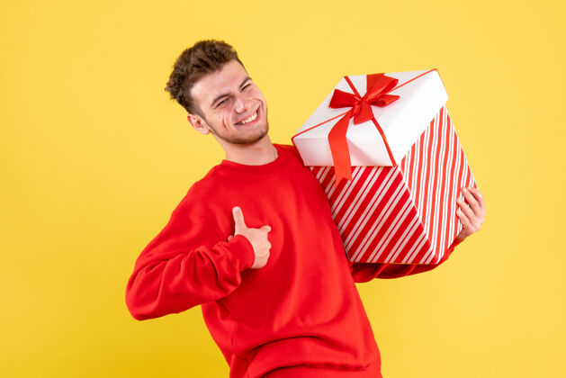 礼物正面图：穿着红色衬衫的年轻男性 带着圣诞礼物年轻圣诞节年轻男性