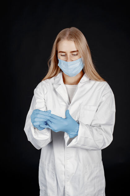 专家戴着医用面罩的医生冠状病毒隔离在黑墙上穿着防护服的女人成人手套诊所