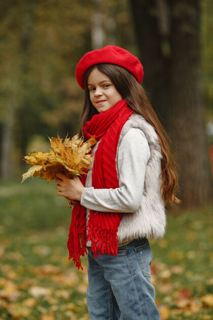 秋天可爱的孩子戴着红色贝雷帽优雅的小女士有一束叶子的孩子年轻健康孩子