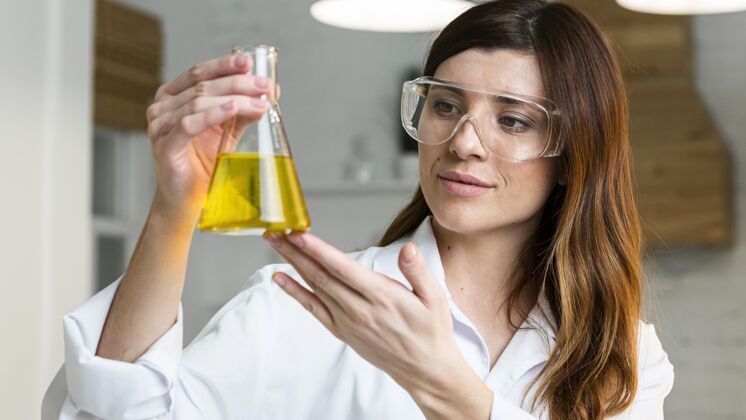 女性戴着安全眼镜拿着试管的女科学家水平检查科学