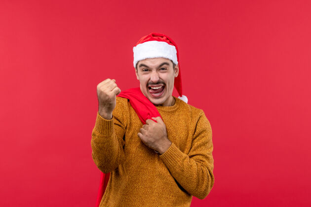 衣服年轻人拿着礼物包在浅红色墙上的正面图光圣诞节脸
