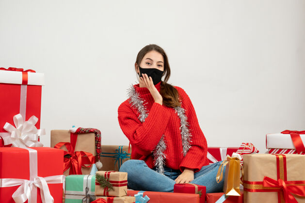 女士穿着红毛衣 戴着黑面具的年轻女孩围坐在一起 送着白底黑面具的礼物年轻女孩购物周围