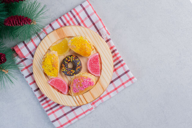 糕点圣诞饼干 甜甜圈和果酱放在深色盘子里圣诞桌布松树