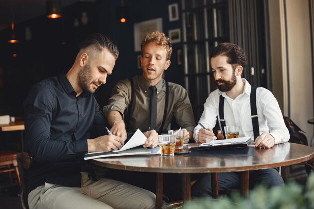 成人谈判中的商人坐在桌边喝酒的男人朋友们在聊天男性办公室专业人士