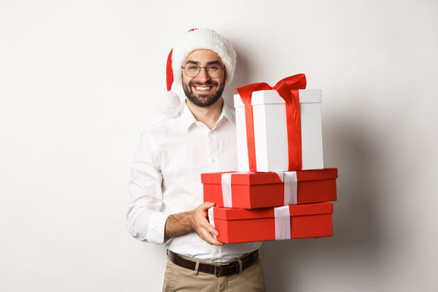 圣诞节圣诞快乐 节日概念快乐的年轻人微笑着 拿着盒子里的礼物 戴着圣诞帽胡须节日商人
