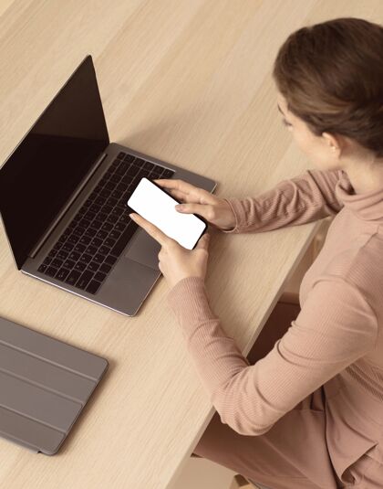 科技坐在笔记本电脑旁使用智能手机的女人姿势科技女人