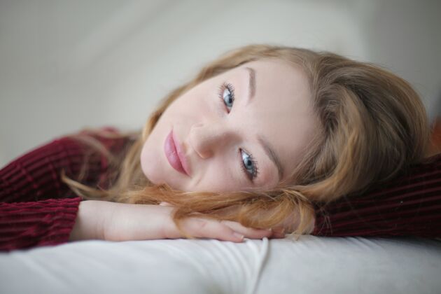 女性躺在床上看着摄像机的金发美女年轻肖像可爱