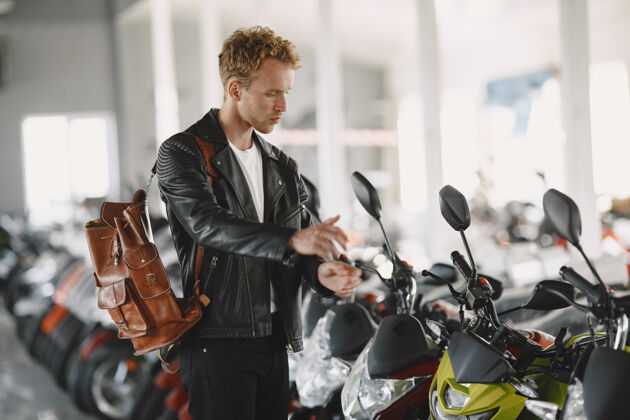 客户一个男人在摩托店里选了摩托车一个穿黑色夹克的家伙阳刚摩托车手购买