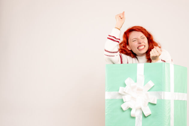 脸一个年轻女子躲在一个白色的墙内礼物的正面视图盒子美丽礼物
