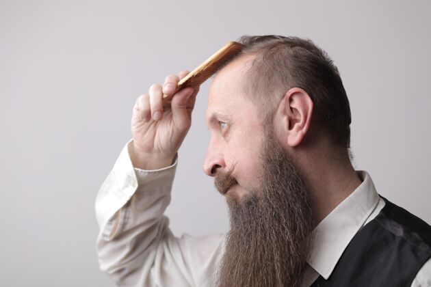 刷子一个留着长胡子的男人在灰色的墙上刷头发事业自信风格