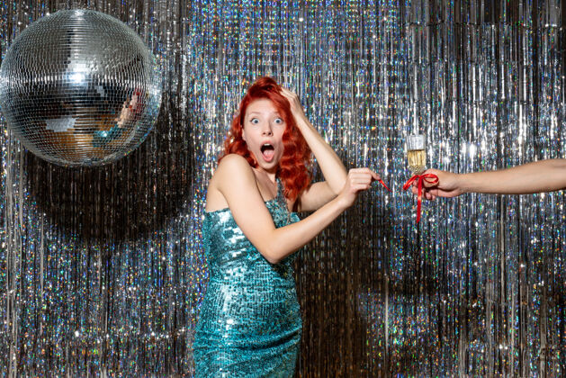 舞蹈年轻的女性在庆祝新年 男性在闪亮的窗帘上建议她的香槟乐趣年模特